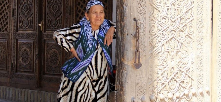 Le sourire accueillant d'une femme Ouzbèque devant le seuil d'une majestueuse porte sculptée.  @ Pixabay